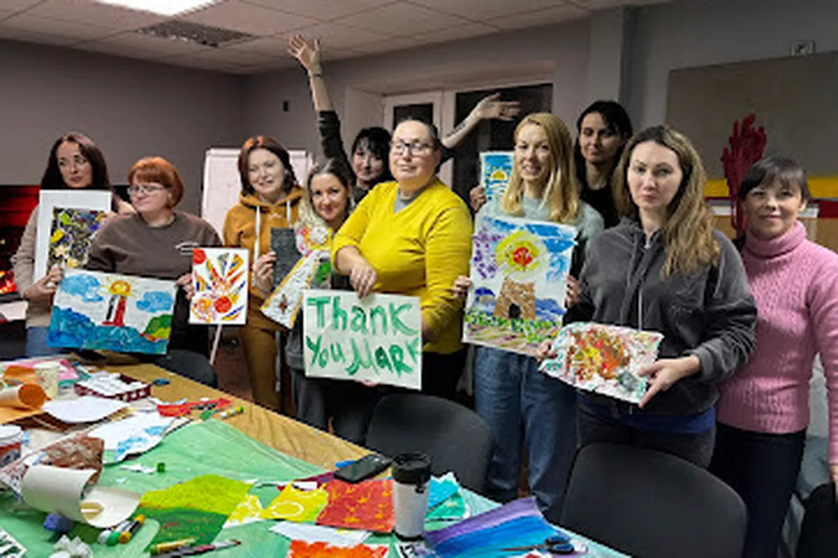 Women and children in Ukraine holding drawings, including one that says Thank you Alaska