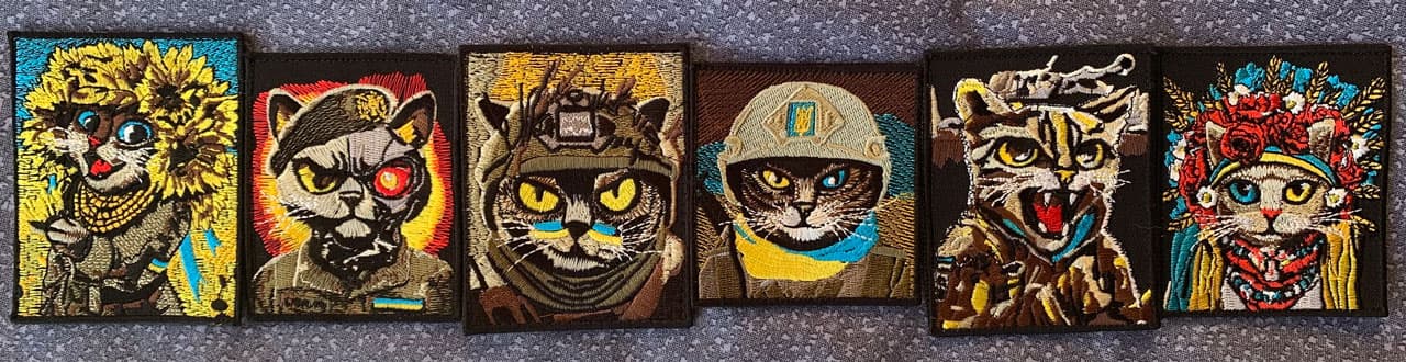 Embroidered cat patches with Ukrainian military/folk motifs arranged in a row