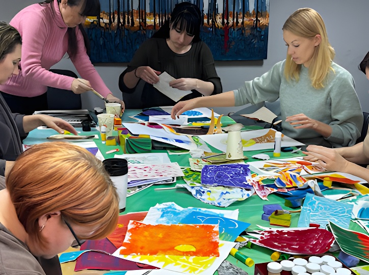 Community art workshop: volunteers creating colorful paper collages at a long table