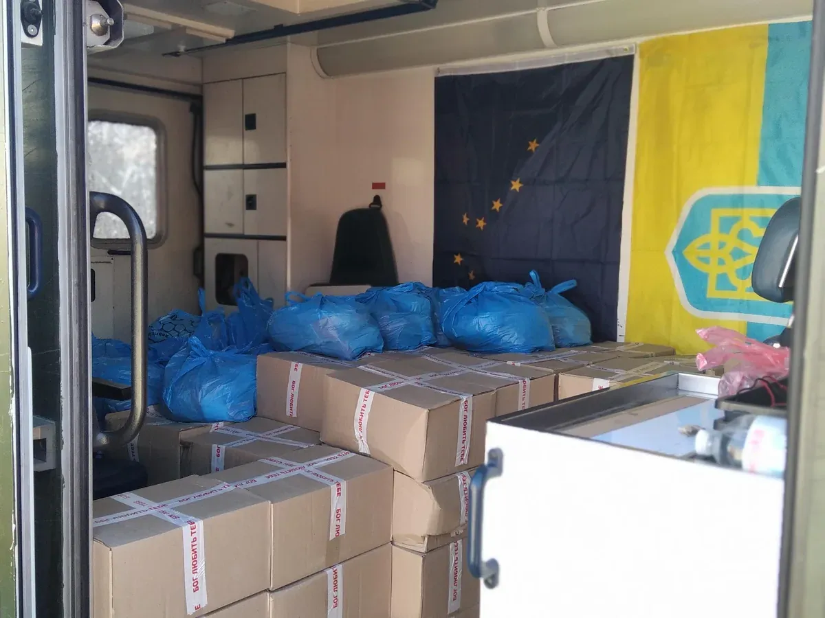 Boxes of aid packed inside an ambulance, with the Alaska and Ukraine flags on the wall